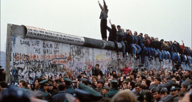 BERLIN, GERMANY - NOVEMBER 12: A man celebrates on the Berlin wall on November 12, 1989 in Berlin, Germany.(Photo by Pool CHUTE DU MUR BERLIN/Gamma-Rapho via Getty Images)